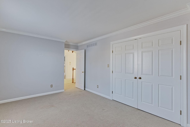 unfurnished bedroom with crown molding, a closet, and light carpet