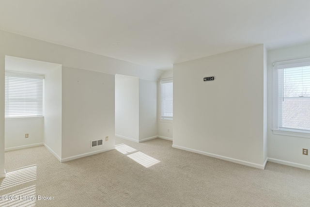 spare room featuring lofted ceiling, light carpet, and plenty of natural light