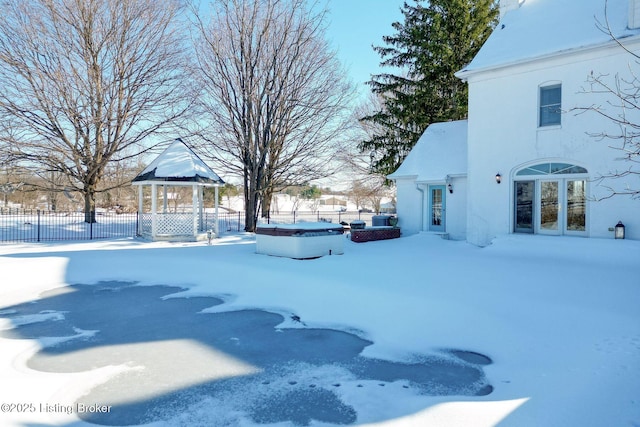 yard covered in snow featuring a hot tub, a patio, and a gazebo