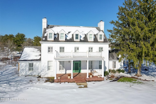 snow covered house with a balcony and covered porch