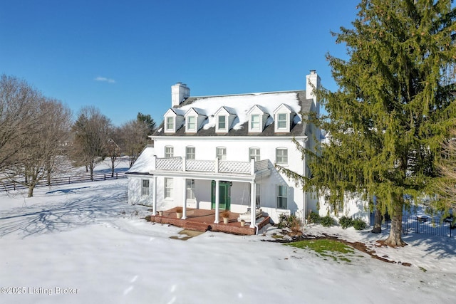 snow covered rear of property with a balcony