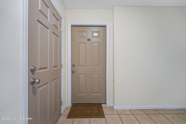 doorway to outside featuring light tile patterned floors and a textured ceiling