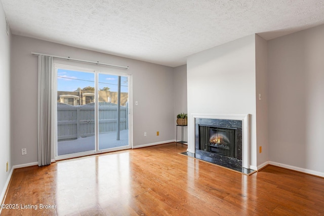 unfurnished living room featuring hardwood / wood-style floors, a premium fireplace, and a textured ceiling