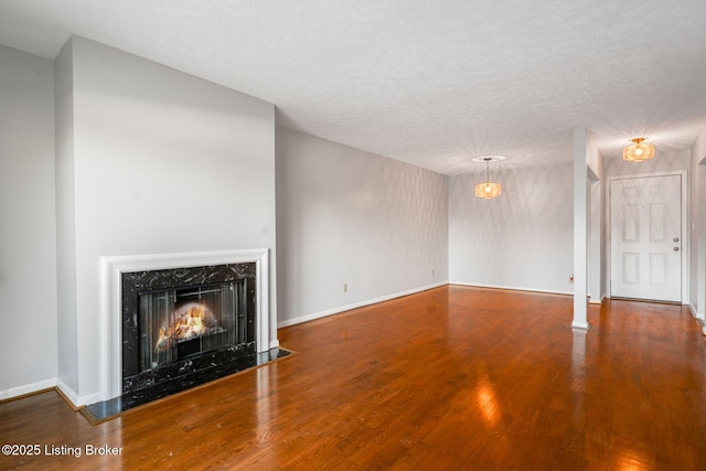 unfurnished living room featuring hardwood / wood-style flooring, a premium fireplace, and a textured ceiling