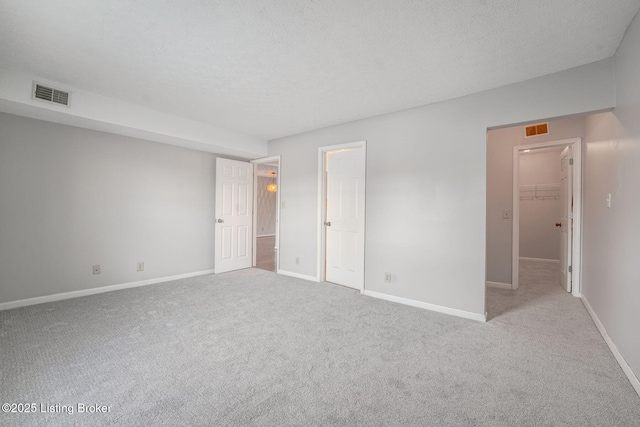 unfurnished room with light carpet and a textured ceiling