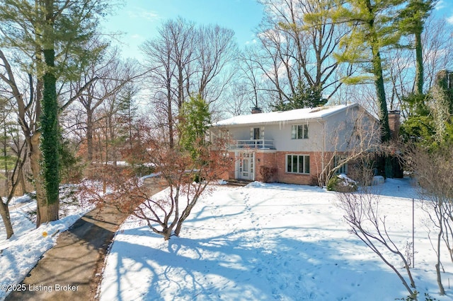 snow covered back of property with a balcony