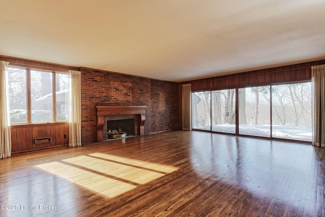 unfurnished living room with plenty of natural light, a fireplace, and wood-type flooring