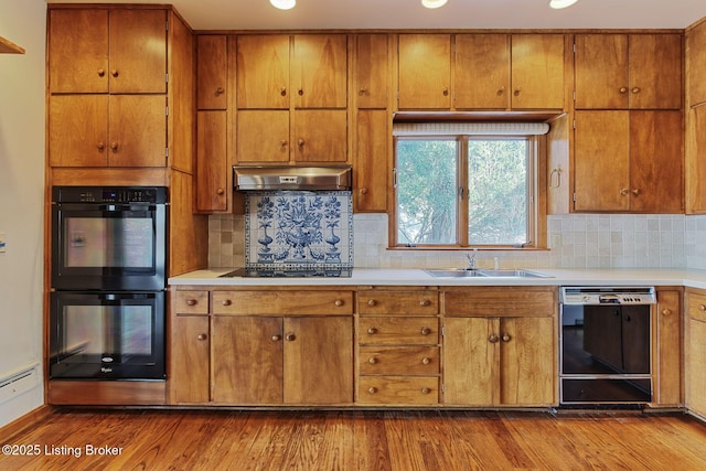 kitchen with black appliances, wood-type flooring, decorative backsplash, and sink