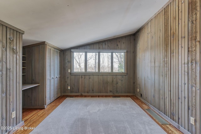 spare room featuring vaulted ceiling and light hardwood / wood-style flooring