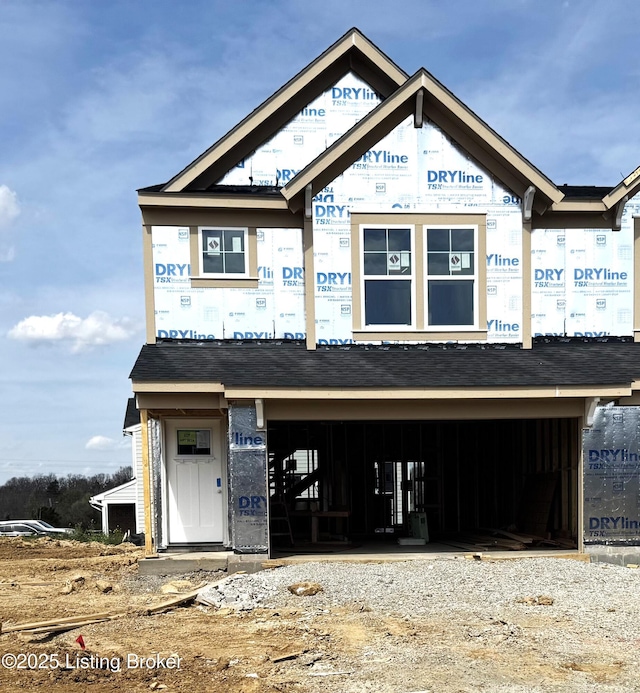 unfinished property with an attached garage and gravel driveway
