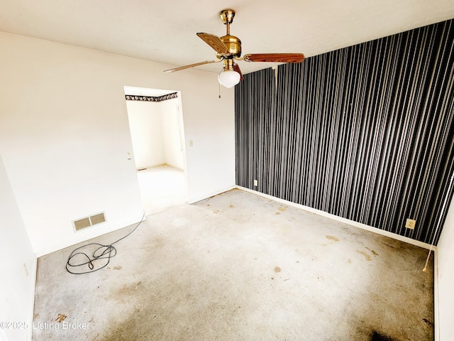 carpeted spare room featuring ceiling fan, visible vents, and baseboards