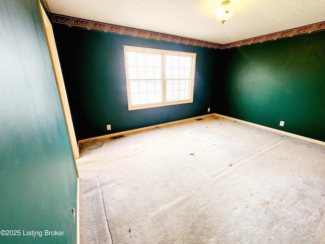 spare room with carpet, visible vents, and baseboards