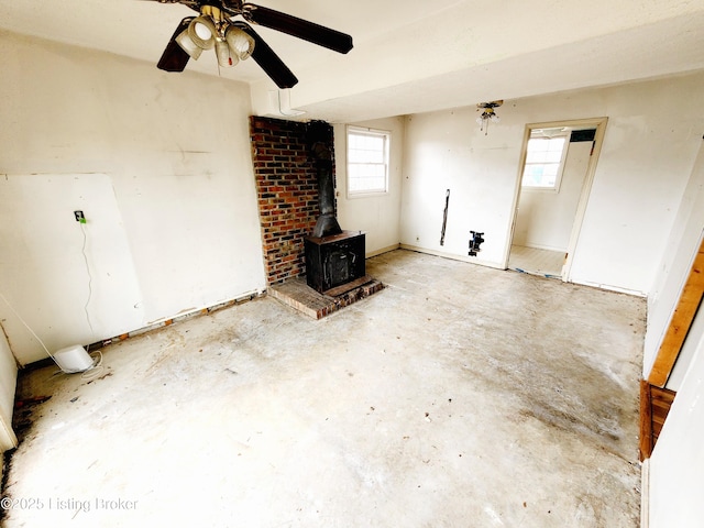 unfurnished living room with a wood stove, plenty of natural light, and concrete floors