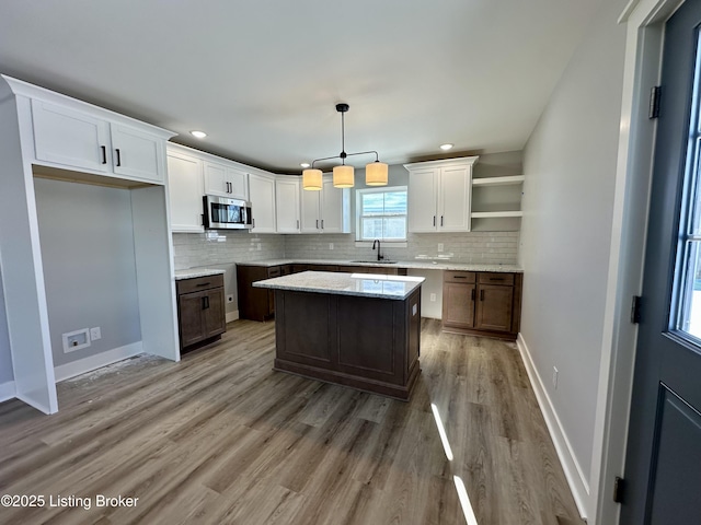 kitchen featuring sink, hanging light fixtures, white cabinetry, and a kitchen island