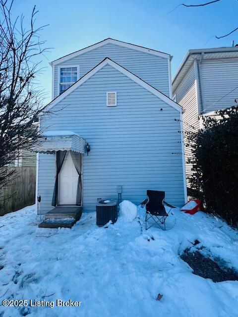 snow covered rear of property featuring central AC unit