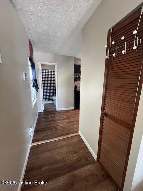 corridor featuring dark wood-type flooring and a textured ceiling