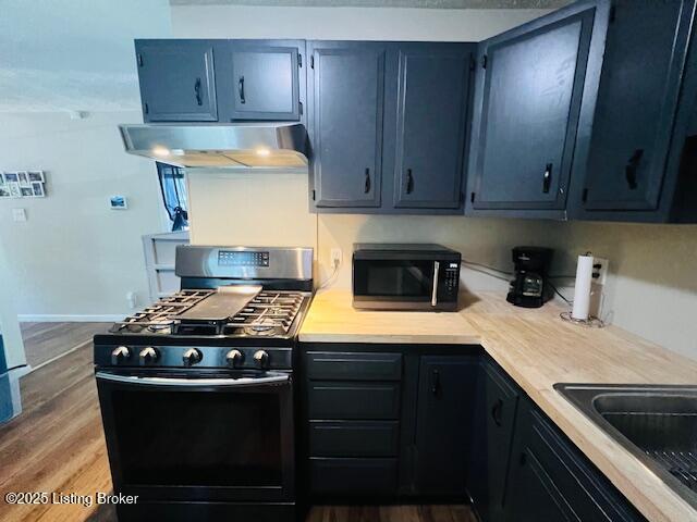 kitchen with stainless steel gas stove, dark wood-type flooring, and exhaust hood