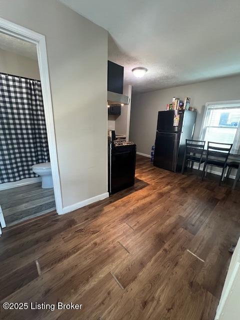 kitchen featuring black fridge, dark hardwood / wood-style floors, and gas range