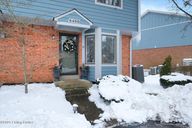 snow covered property entrance with central AC unit