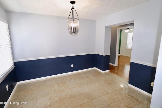 unfurnished room with a textured ceiling and a chandelier