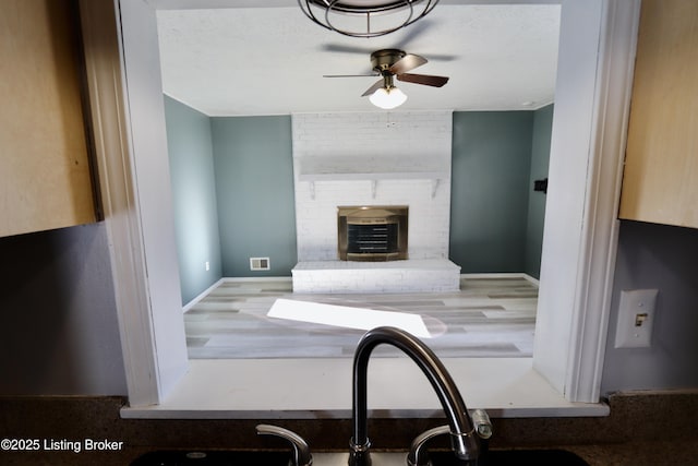 kitchen with sink, a fireplace, and ceiling fan