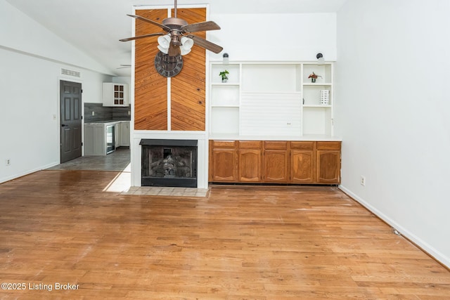 unfurnished living room featuring ceiling fan, lofted ceiling, beverage cooler, and light hardwood / wood-style flooring