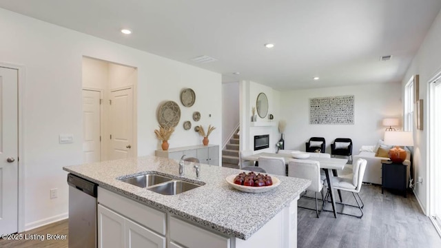 kitchen featuring dishwasher, white cabinets, sink, dark hardwood / wood-style floors, and an island with sink