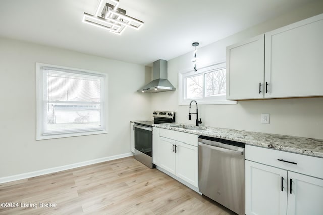 kitchen featuring white cabinetry, sink, wall chimney exhaust hood, light stone countertops, and appliances with stainless steel finishes