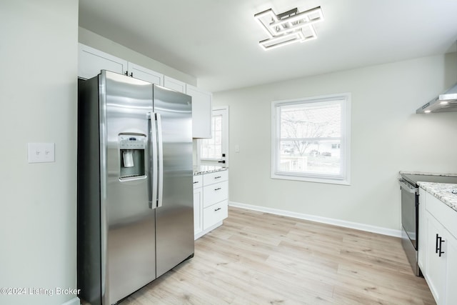 kitchen featuring light stone countertops, white cabinets, light wood-type flooring, and appliances with stainless steel finishes