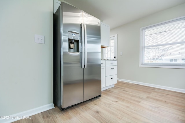 kitchen featuring stainless steel fridge with ice dispenser, light hardwood / wood-style floors, white cabinetry, and light stone counters