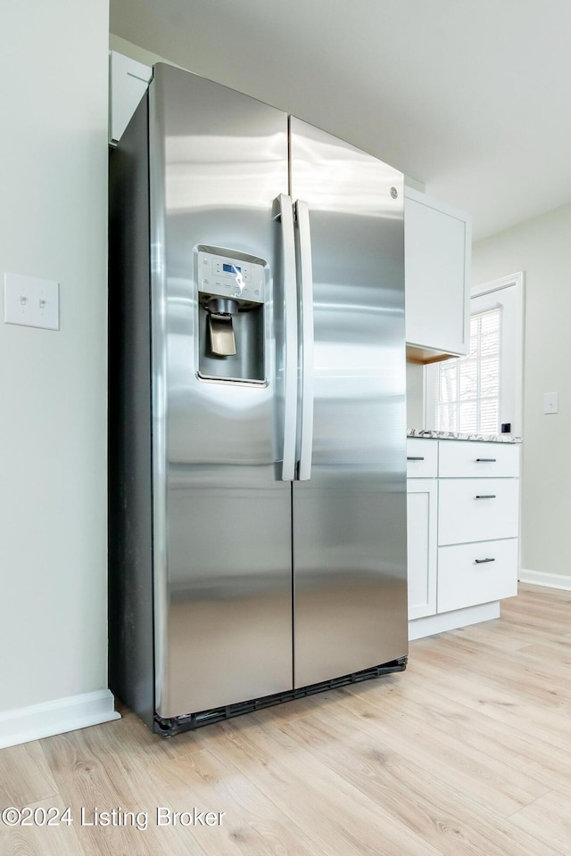 kitchen with white cabinetry, light stone counters, stainless steel fridge with ice dispenser, and light hardwood / wood-style flooring