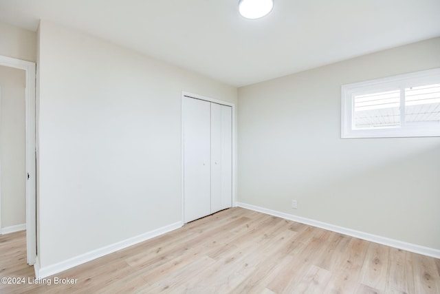 unfurnished bedroom with light wood-type flooring and a closet