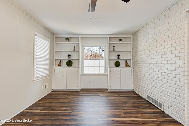 entrance foyer featuring ceiling fan, brick wall, and dark hardwood / wood-style floors