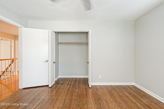 unfurnished bedroom featuring a closet, dark hardwood / wood-style flooring, and ceiling fan