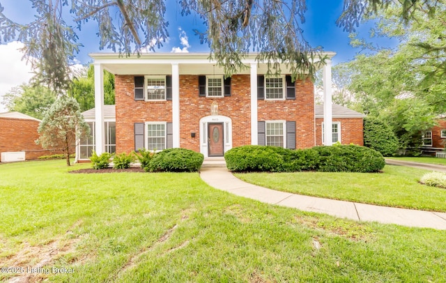 neoclassical home featuring brick siding and a front lawn