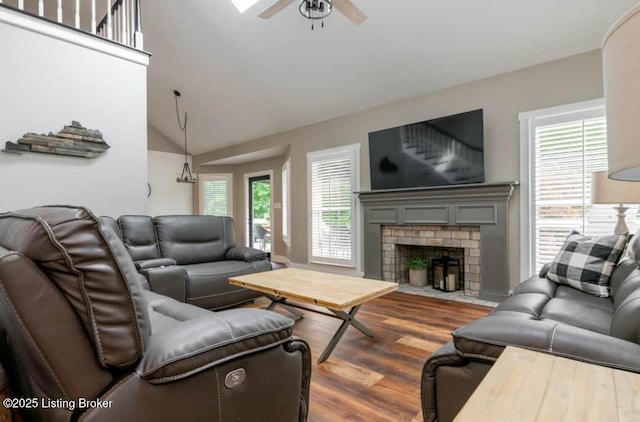 living room with ceiling fan, lofted ceiling, dark wood-type flooring, and a brick fireplace