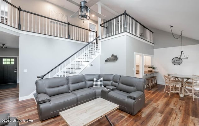 living room with a towering ceiling, ceiling fan, and dark wood-type flooring