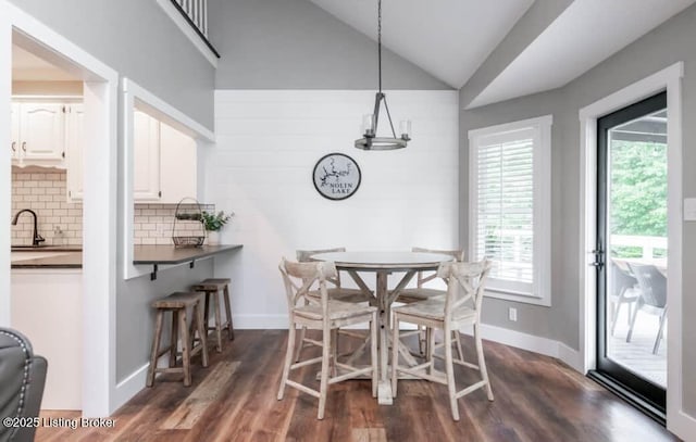 dining room featuring dark hardwood / wood-style flooring, vaulted ceiling, and sink