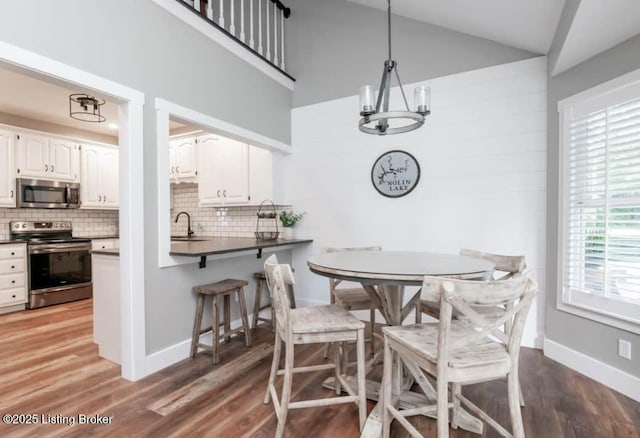 dining space featuring a healthy amount of sunlight, dark wood-type flooring, lofted ceiling, and sink