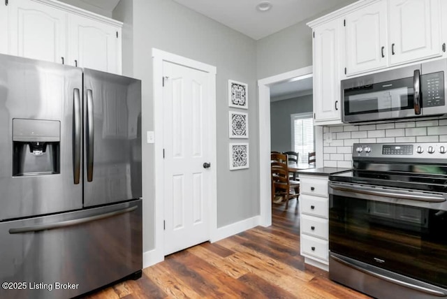 kitchen with backsplash, white cabinetry, dark wood-type flooring, and appliances with stainless steel finishes