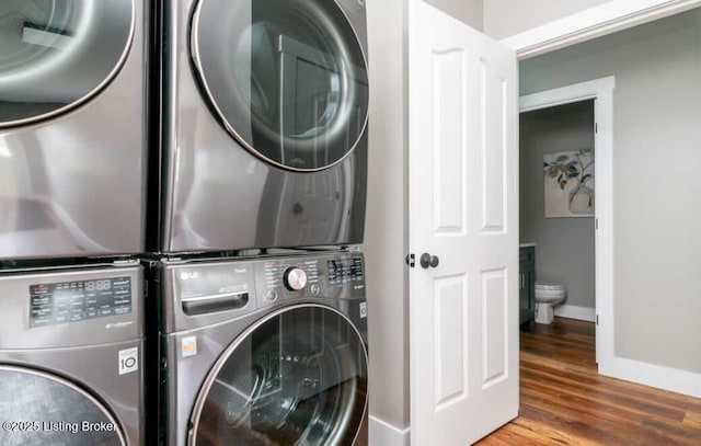 laundry area with hardwood / wood-style flooring and stacked washer / drying machine