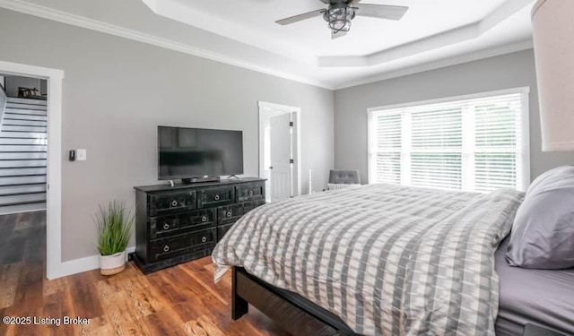 bedroom with dark hardwood / wood-style floors, a raised ceiling, ceiling fan, and ornamental molding