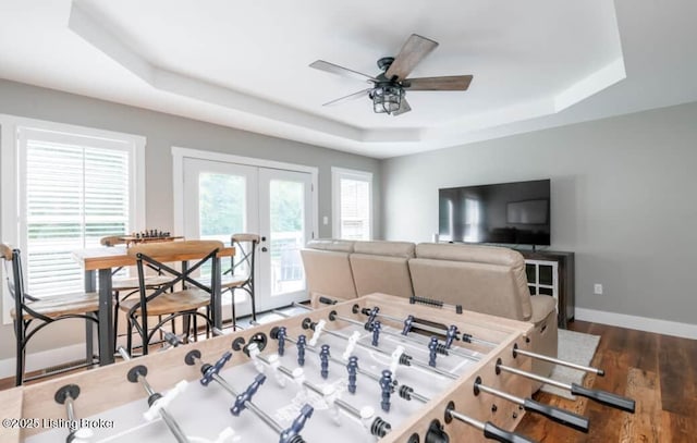 game room with french doors, dark hardwood / wood-style floors, a raised ceiling, and a wealth of natural light