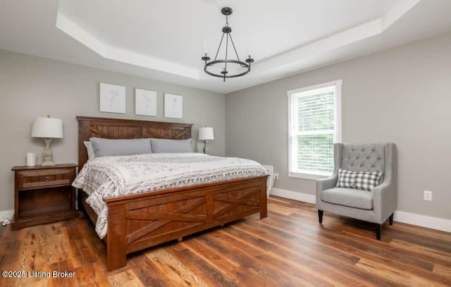 bedroom with dark hardwood / wood-style flooring and a tray ceiling