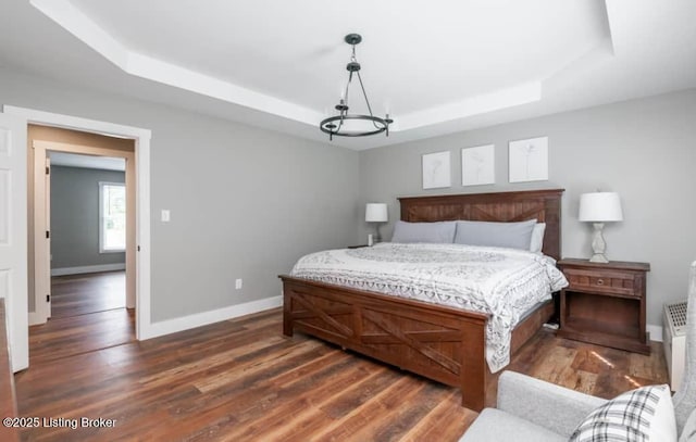 bedroom with dark hardwood / wood-style flooring and a tray ceiling