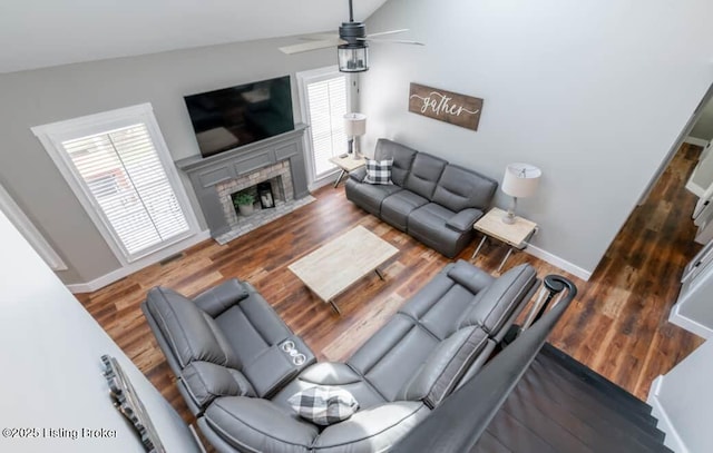 living room with dark hardwood / wood-style flooring, a brick fireplace, ceiling fan, and lofted ceiling