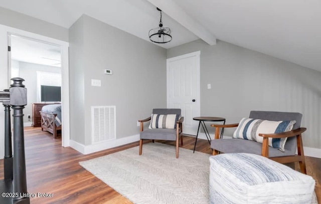 living area with a chandelier, hardwood / wood-style floors, and vaulted ceiling with beams