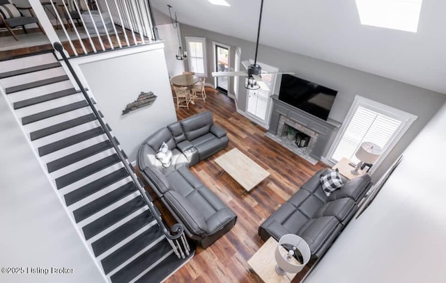 living room with a stone fireplace, dark hardwood / wood-style flooring, and lofted ceiling