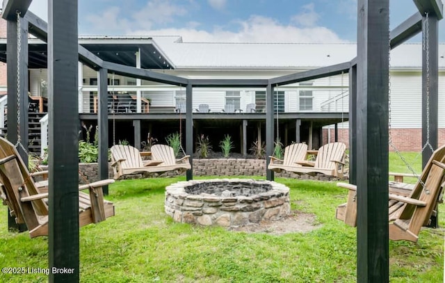 back of house featuring a fire pit and a lawn