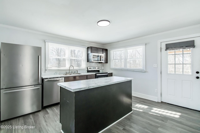 kitchen featuring sink, a center island, light hardwood / wood-style flooring, crown molding, and appliances with stainless steel finishes